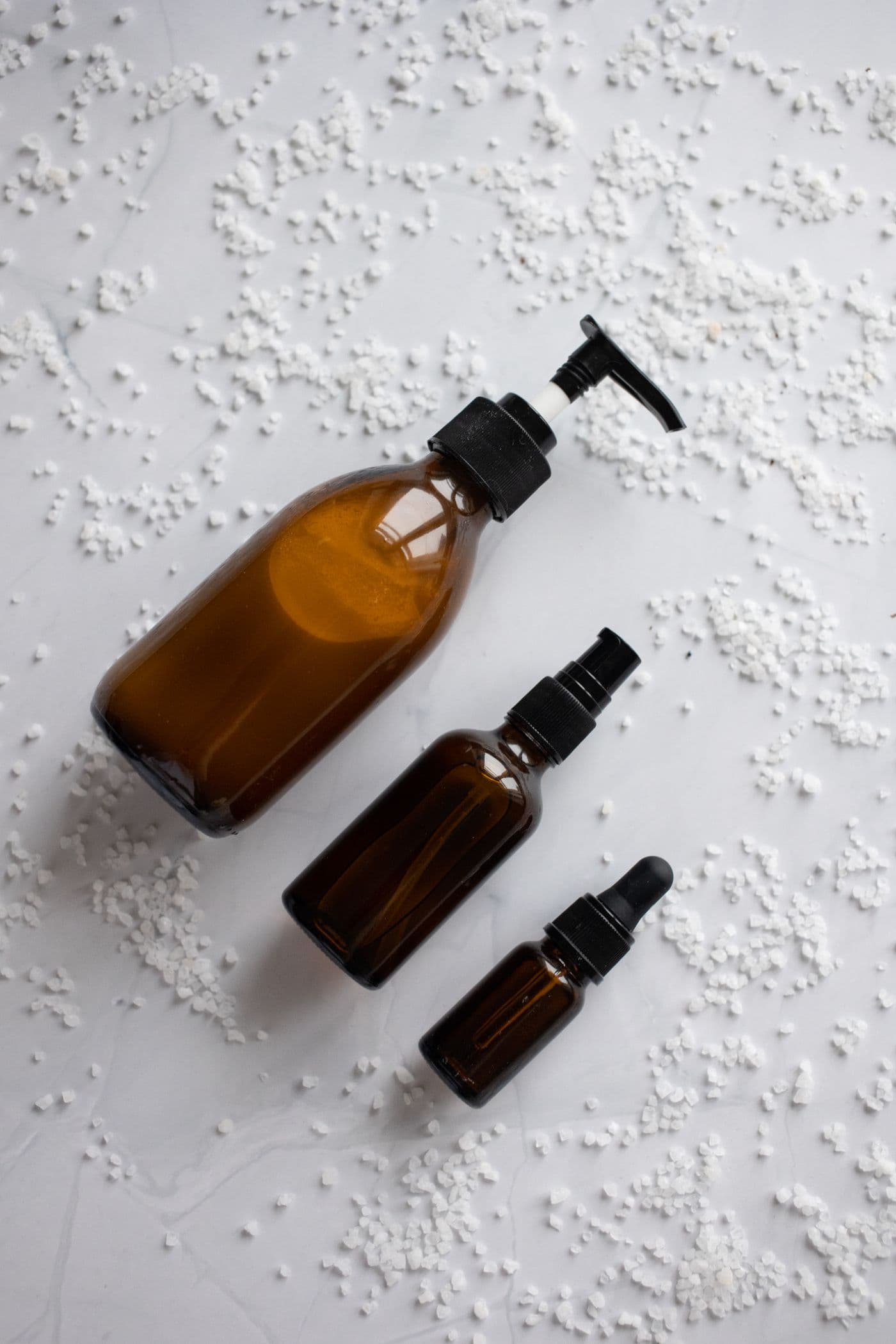 Three amber glass skincare bottles on a light surface